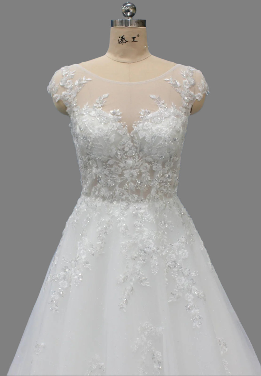 White lace wedding dress on a mannequin against a blue wall